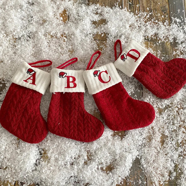 "Barn julstrumpor, röd med broderad bokstav och färgglatt godismönster, perfekt för juldekoration och barnens glädje."