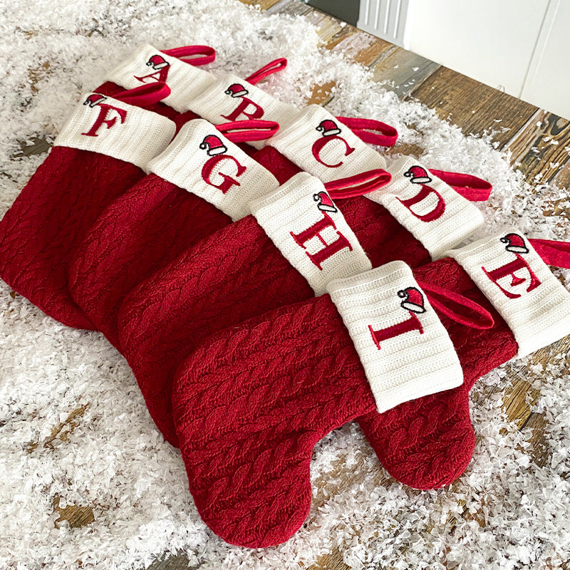 "Barn julstrumpor, röd med broderad bokstav och färgglatt godismönster, perfekt för juldekoration och barnens glädje."