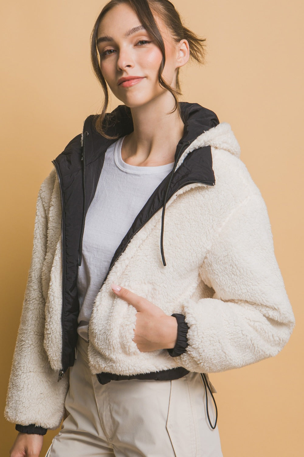 "Damernas vändbara cropped jacka med huva, sherpa på ena sidan, nylon på andra, sett framifrån för urban stil."