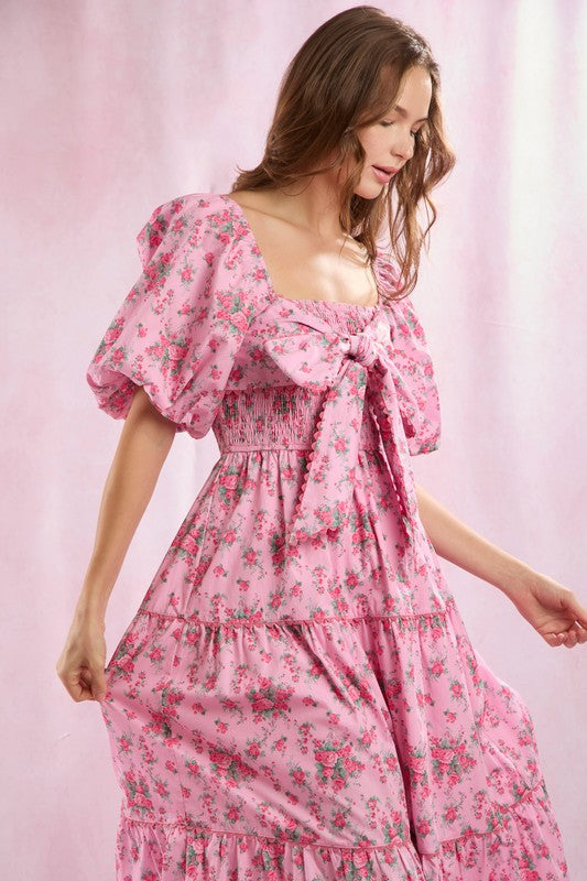 "Elegant blommönstrad dammaxiklänning med framknutning, lång längd och romantisk stil för sommarfester."