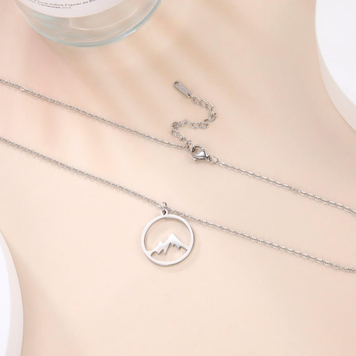 "Elegant damhalsband med bergshänge i rostfritt stål, myntformat, två snöiga bergstoppar, symbol för styrka och mod."
