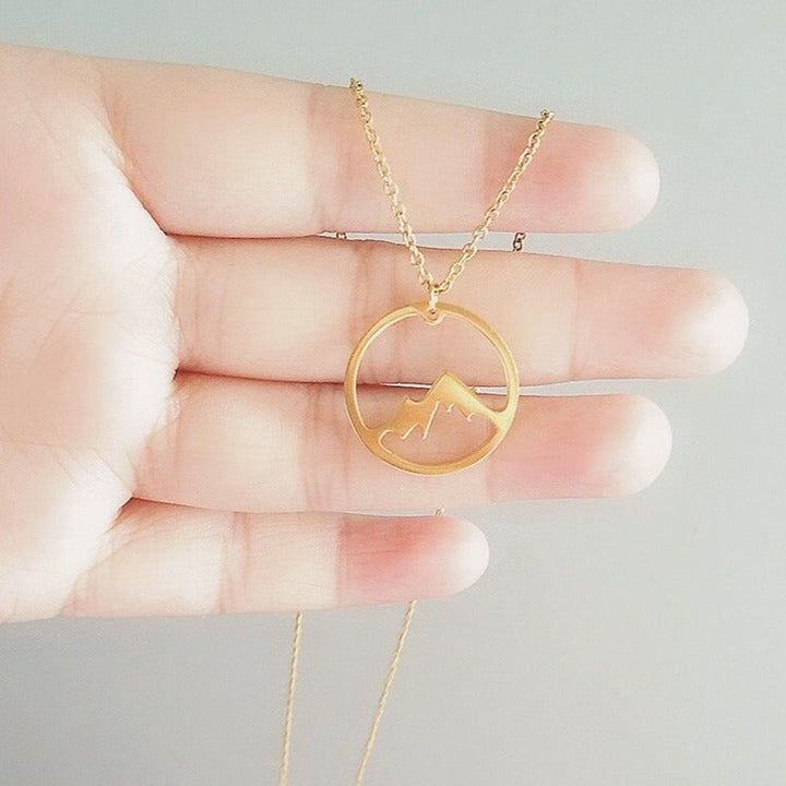 "Elegant damhalsband med bergshänge i rostfritt stål, myntformat, två snöiga bergstoppar, symbol för styrka och mod."