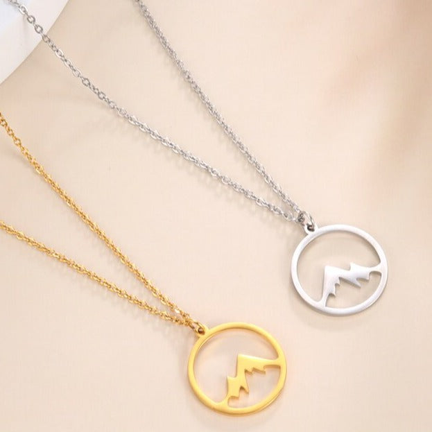 "Elegant damhalsband med bergshänge i rostfritt stål, myntformat, två snöiga bergstoppar, symbol för styrka och mod."