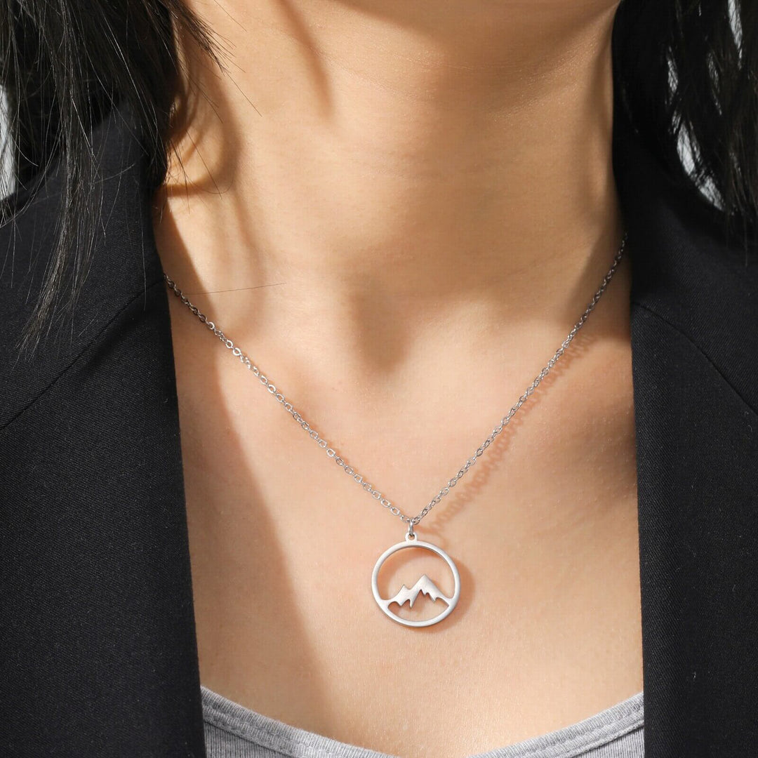 "Elegant damhalsband med bergshänge i rostfritt stål, myntformat, två snöiga bergstoppar, symbol för styrka och mod."
