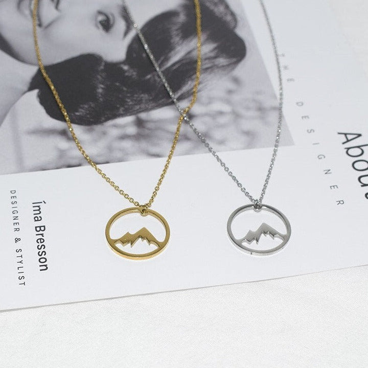 "Elegant damhalsband med bergshänge i rostfritt stål, myntformat, två snöiga bergstoppar, symbol för styrka och mod."