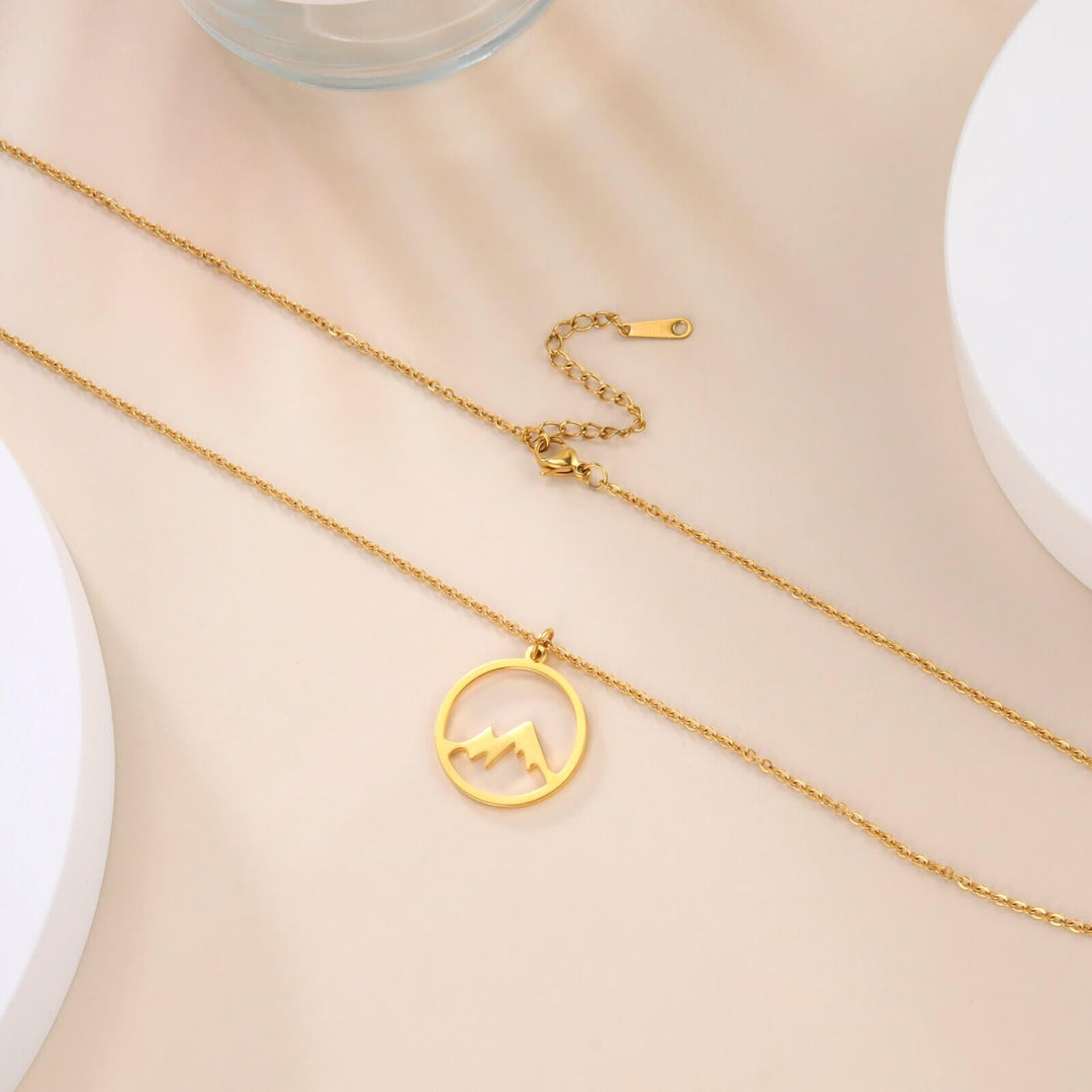 "Elegant damhalsband med bergshänge i rostfritt stål, myntformat, två snöiga bergstoppar, symbol för styrka och mod."