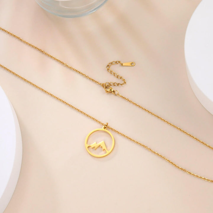 "Elegant damhalsband med bergshänge i rostfritt stål, myntformat, två snöiga bergstoppar, symbol för styrka och mod."