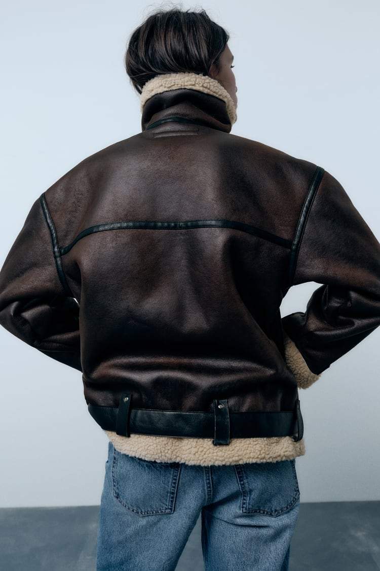 "Elegant damjacka med revers i vattenavvisande konstmaterial, visad framifrån med klassiska skärningar och stilren design."