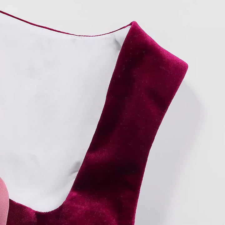 Elegant dirndl klänning med burgundy blommönster och klassiskt svart förkläde, perfekt för Oktoberfest.