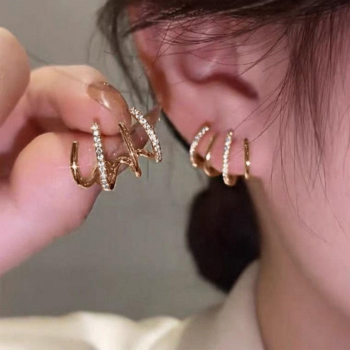 "Elegant klor örhängen med kubisk zirkonia, guldfärg, feminin design, ger illusion av flera piercingar, kvinnor."