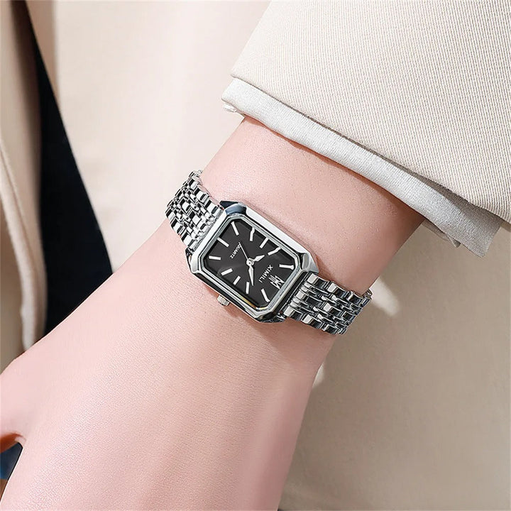 Elegant kvadratisk kvinnoarmbandsklocka i guld och silver med fyrkantig urtavla och glänsande metallarmband.