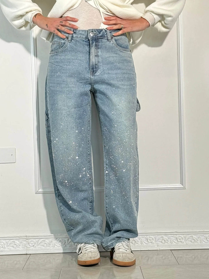 En dam som bär svarta jeans med diamantdetaljer, bekväm passform, perfekt för både vardag och fest.