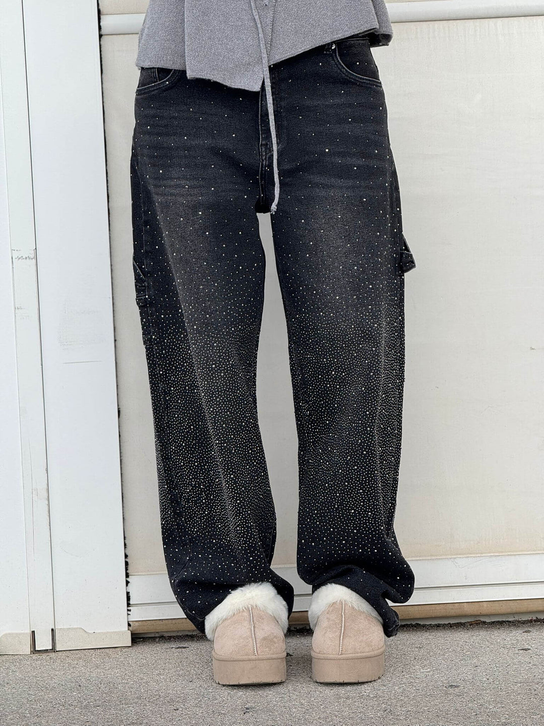 En dam som bär grå jeans med diamantdetaljer, bekväm passform, perfekt för både vardag och fest.