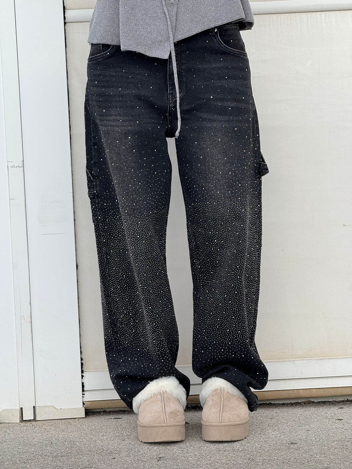 En dam som bär grå jeans med diamantdetaljer, bekväm passform, perfekt för både vardag och fest.
