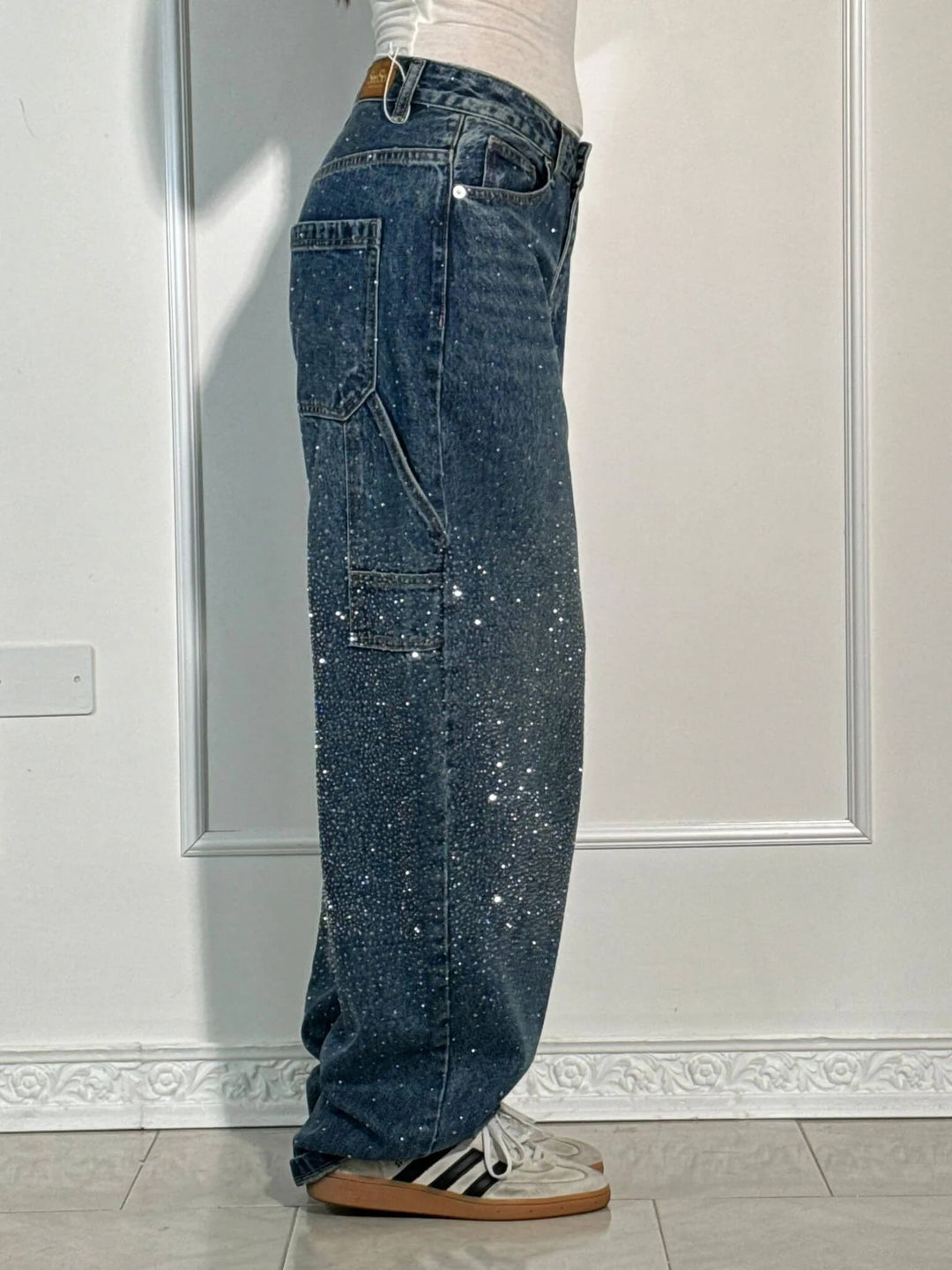 Detaljer av mörkblå damjeans med glittrande diamantdekor, bekväm passform, perfekt för både vardag och fest.
