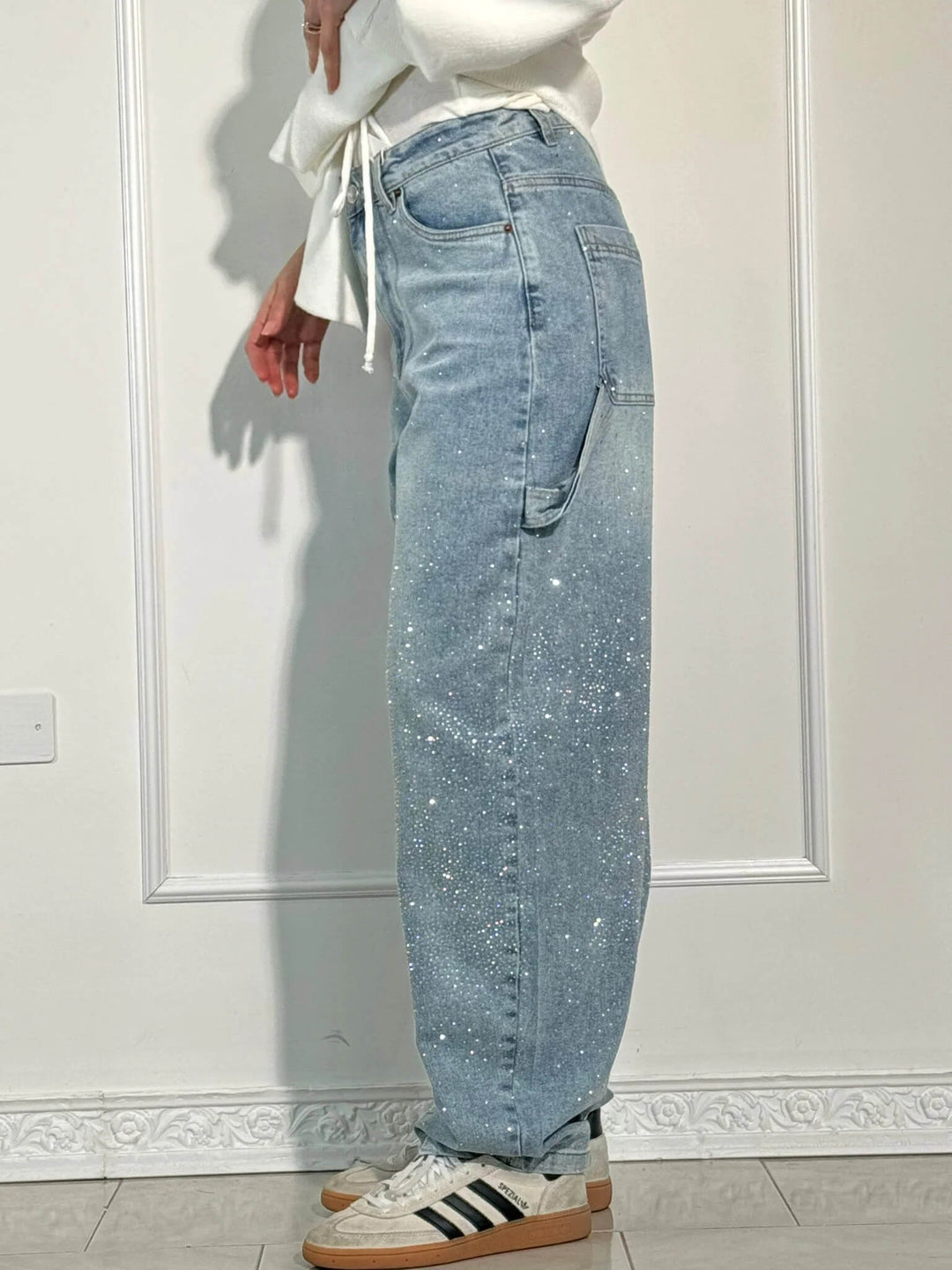 Detaljer av svarta damjeans med glittrande diamantdekor, bekväm passform, perfekt för både vardag och fest.