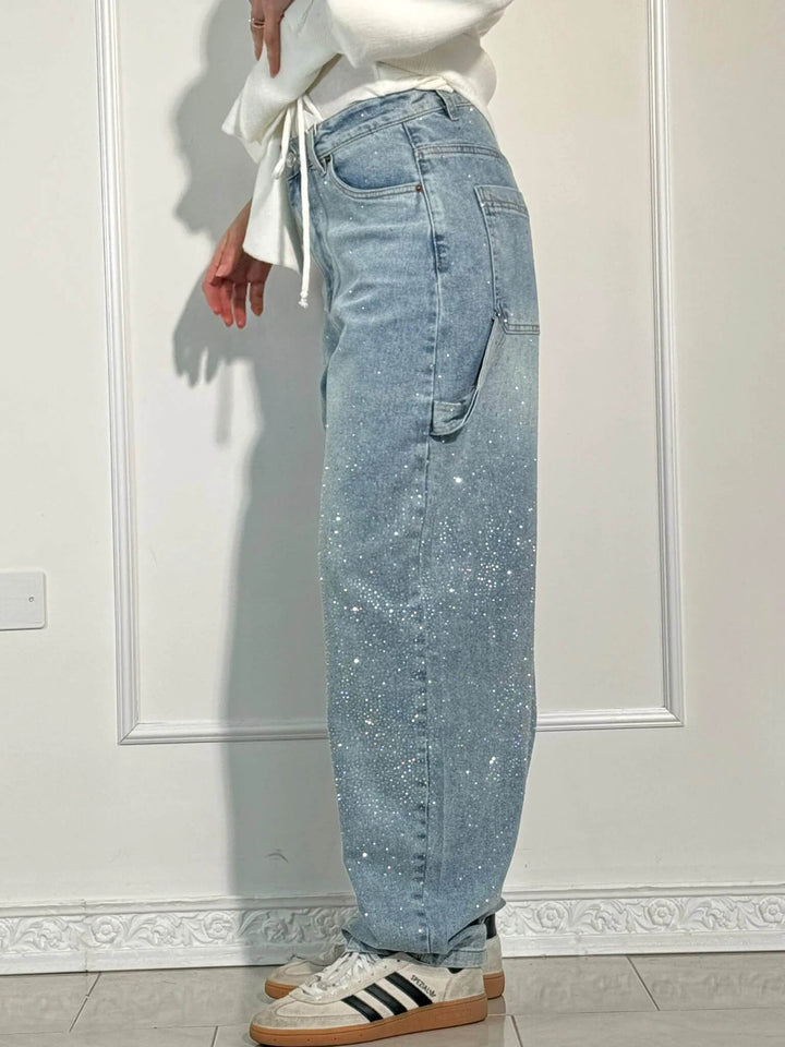Detaljer av svarta damjeans med glittrande diamantdekor, bekväm passform, perfekt för både vardag och fest.