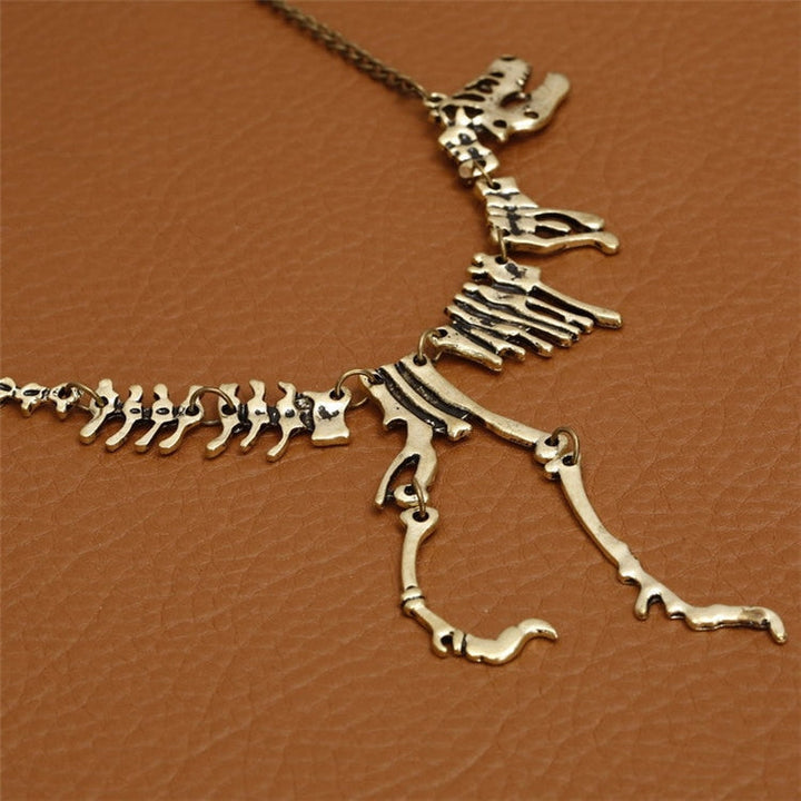 "Halsband med detaljerat T-Rex-skelett, rörlig design i brons och guld. Perfekt för damer som älskar dinosaurier."