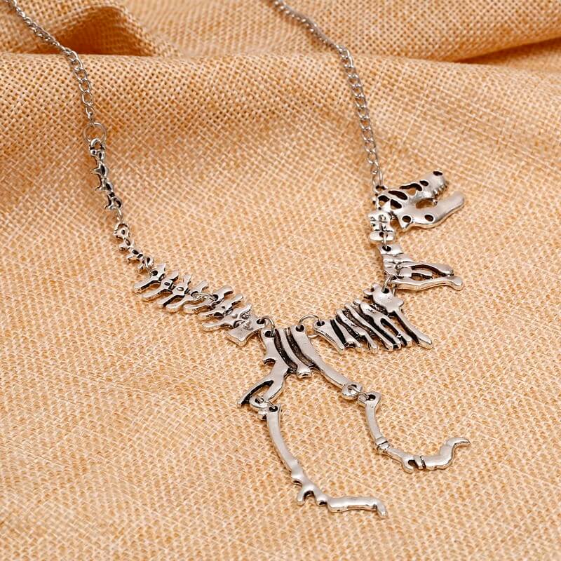 "Halsband med detaljerat T-Rex-skelett, rörlig design i brons och guld. Perfekt för damer som älskar dinosaurier."
