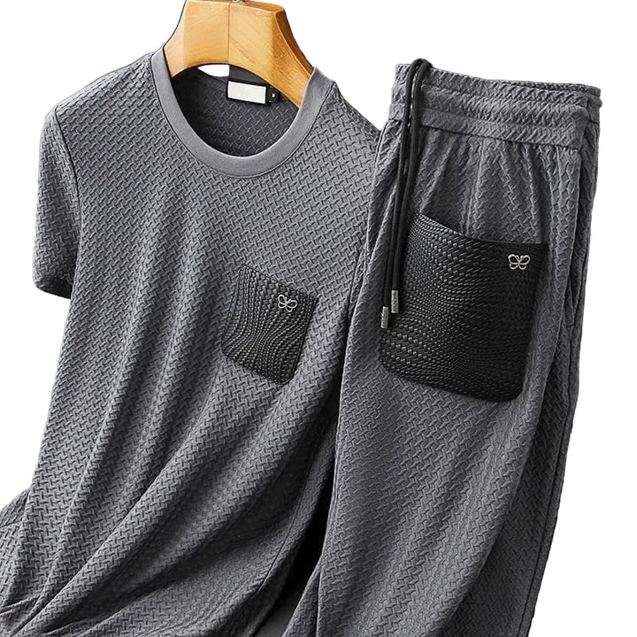 "Herrgrå-svart tvådelat set framifrån, t-shirt och byxor, kortärmad och rak benprofil, avslappnad stil."