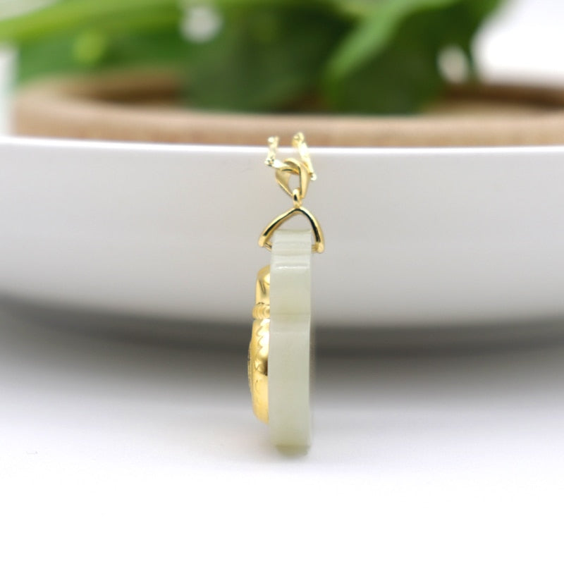 "Hängsmycke för kvinnor med Feng Shui inspiration, grön Hetian-jade och pengaväska symbol, i guldfärgad metall."