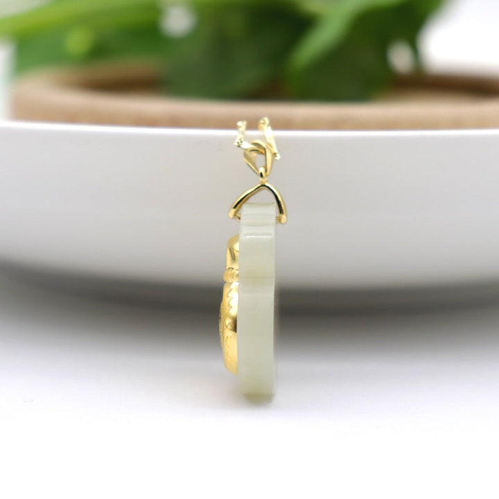 "Hängsmycke för kvinnor med Feng Shui inspiration, grön Hetian-jade och pengaväska symbol, i guldfärgad metall."