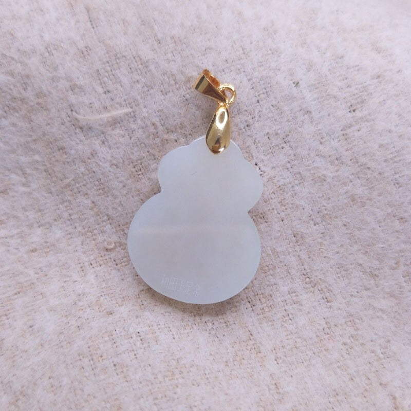 "Hängsmycke för kvinnor med Feng Shui inspiration, grön Hetian-jade och pengaväska symbol, i guldfärgad metall."