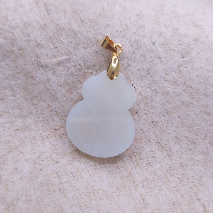 "Hängsmycke för kvinnor med Feng Shui inspiration, grön Hetian-jade och pengaväska symbol, i guldfärgad metall."