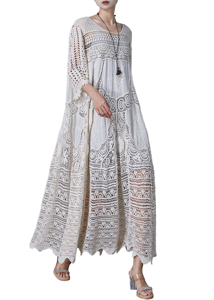Kvinna i lång vit spetsklänning med romantisk oversized design, chic och bekväm för sommar eller kväll.