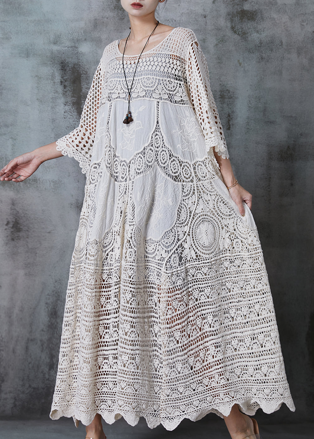 Kvinna i lång vit spetsklänning med romantisk oversized design, chic och bekväm för sommar eller kväll.