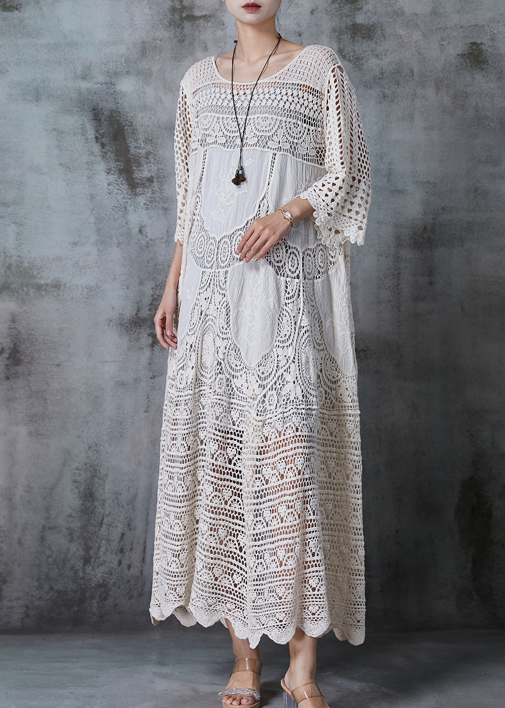 Kvinna i lång vit spetsklänning med romantisk oversized design, chic och bekväm för sommar eller kväll.