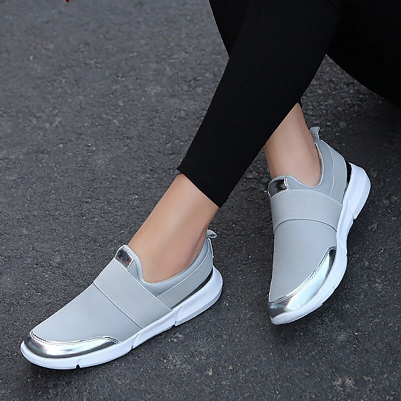 "Kvinnors andningsbara grå och svarta slip-on skor med modern design och stretchmaterial för bekväm daglig användning."