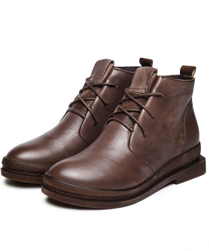"Kvinnors bruna Martens-stövlar i läder med korsremmar och robust sula, perfekt för en stilren look."