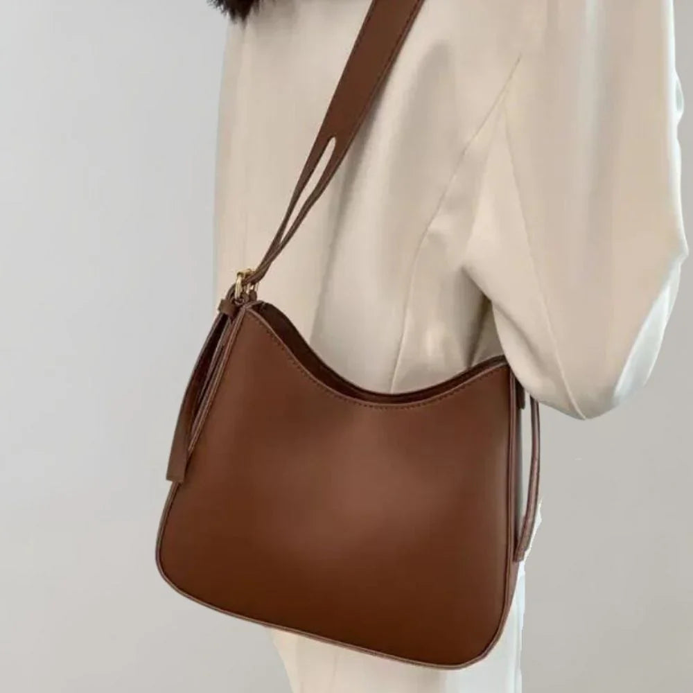 Dam Crossbody-väska med strukturerad design, guldaccenter, justerbar rem, elegant och funktionell för modern stil.