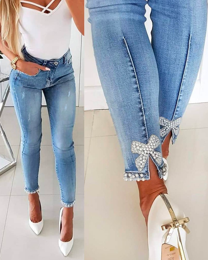 "Kvinnors denimbyxor med unik bågknut och pärldetaljer, formflatterande design, perfekt för alla tillfällen."