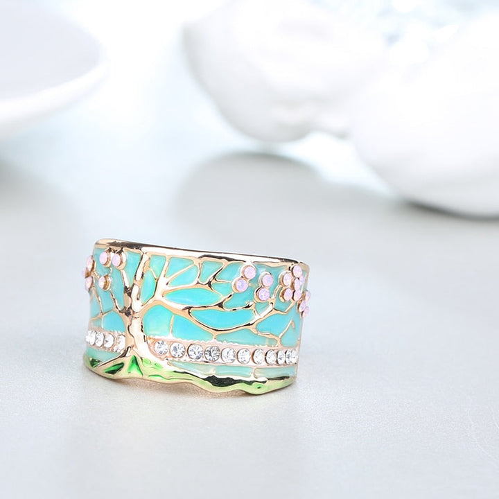 "Kvinnors elegant opalring med livets träd, i blått och grönt, symbol för styrka och stil, perfekt accessoar."