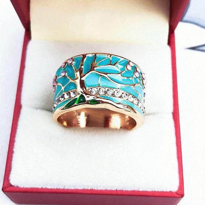 "Kvinnors elegant opalring med livets träd, i blått och grönt, symbol för styrka och stil, perfekt accessoar."
