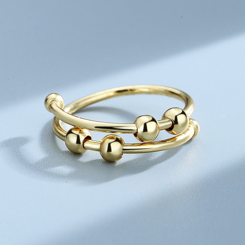 "Kvinnors justerbara fidget ring med pärlor, guld och silver, geometrisk design, lugnande accessoar mot stress."