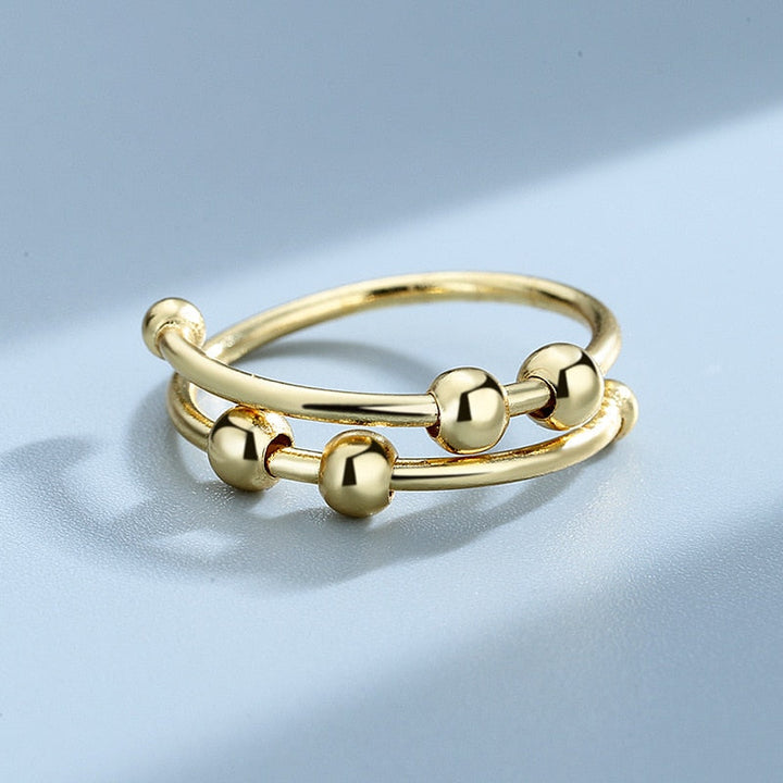 "Kvinnors justerbara fidget ring med pärlor, guld och silver, geometrisk design, lugnande accessoar mot stress."