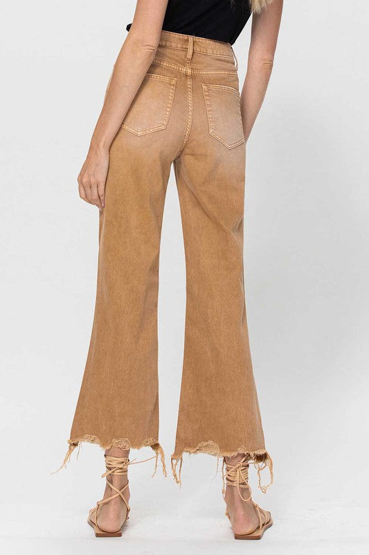 "Kvinnors vintage guld crop flare jeans, 90-talsstil, trendig flair, avslappnad passform mot bakgrund av natur."