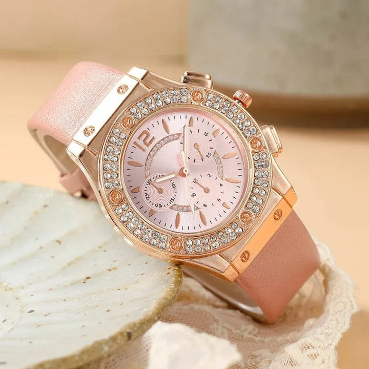 "Lyxig damklocka med strass, rosa band och kvartsurverk. Elegant och gnistrande design för en sofistikerad look."