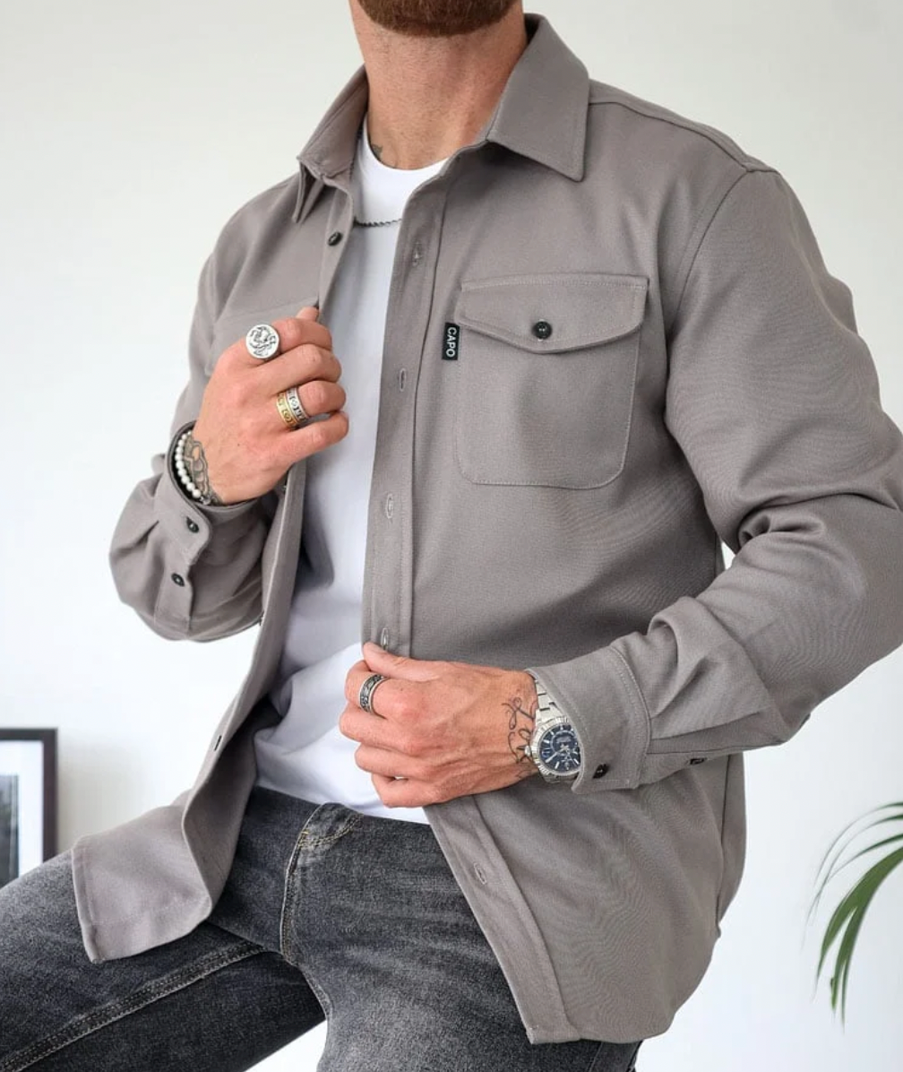 Modern herrskjorta i mjukt tyg, grå färg, stilrent snitt, perfekt för kontor och vardag. Komfort och elegans för män.