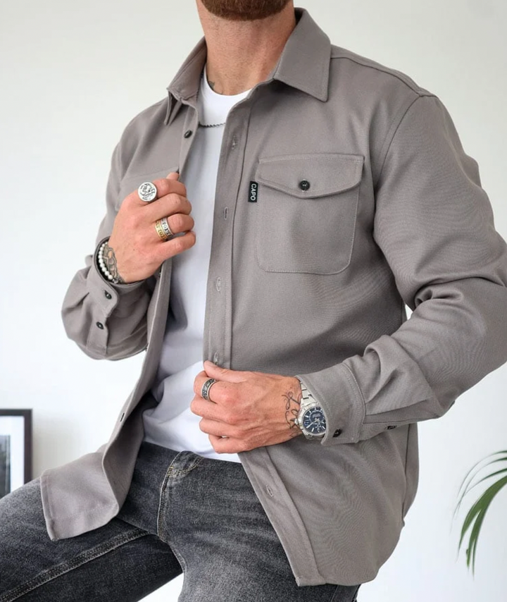 Modern herrskjorta i mjukt tyg, grå färg, stilrent snitt, perfekt för kontor och vardag. Komfort och elegans för män.