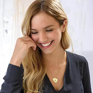 "Personligt halsband i guld med babyfötter och graverade namn, perfekt för mödrar, moderna och elegant design."