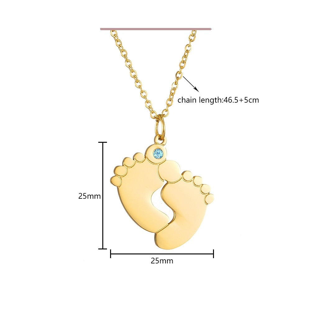 "Personligt halsband i guld med babyfötter och graverade namn, perfekt för mödrar, moderna och elegant design."