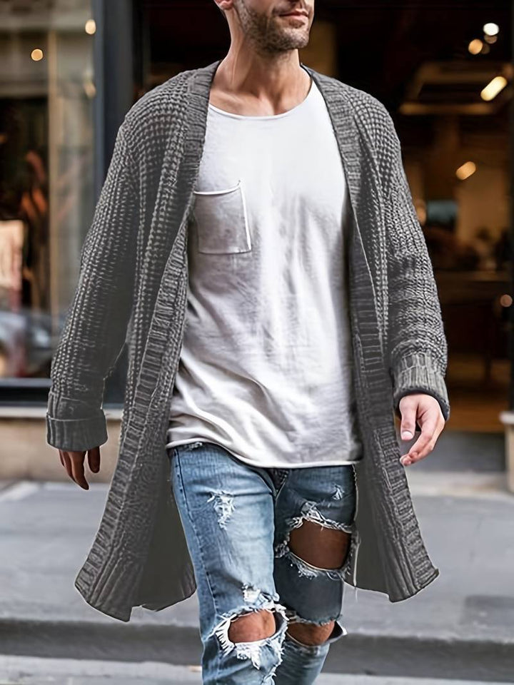 "Stickad herr cardigan i mjukt material med minimalistisk design, visad framifrån med klassiskt knappslut och rund hals."