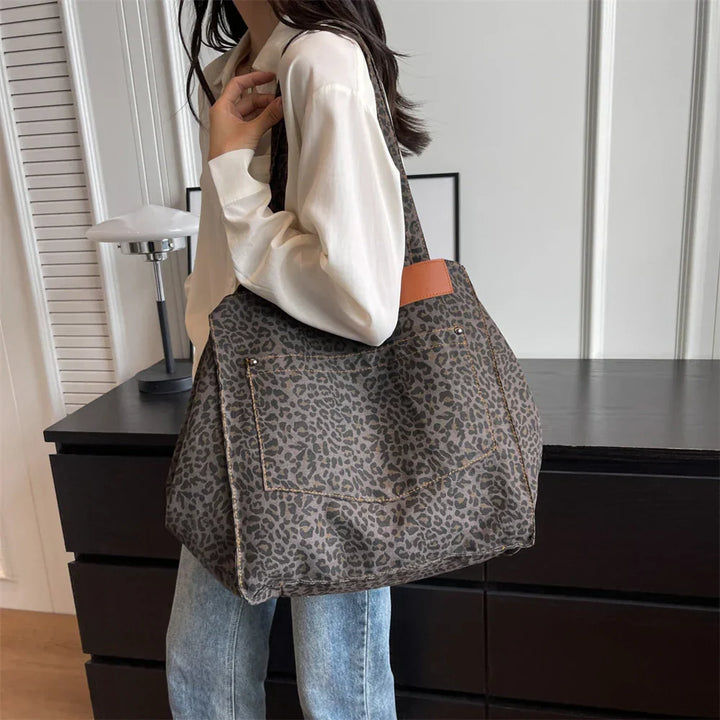 "Stilren damoversized axelväska i leopardmönstrad canvas med stora fickor, perfekt accessoar för en djärv och praktisk look."