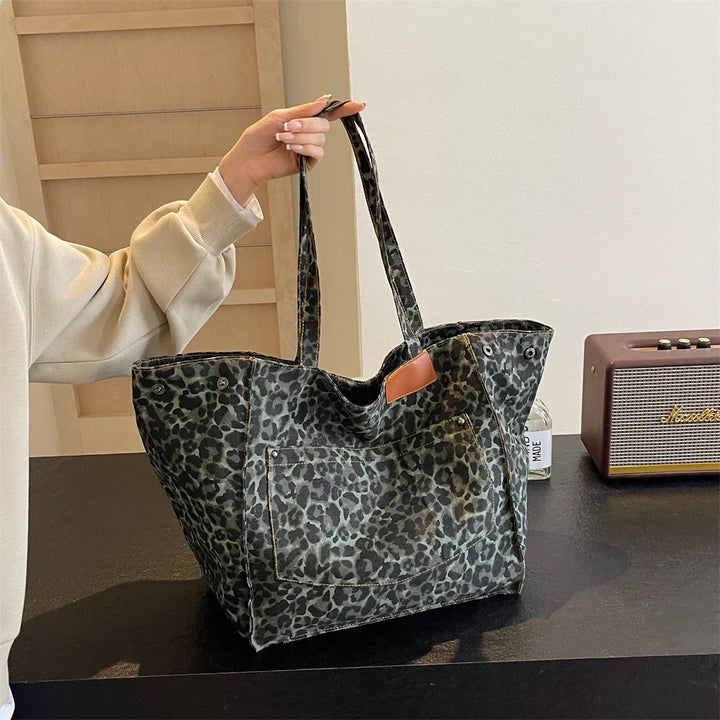 "Stilren damoversized axelväska i leopardmönstrad canvas med stora fickor, perfekt accessoar för en djärv och praktisk look."