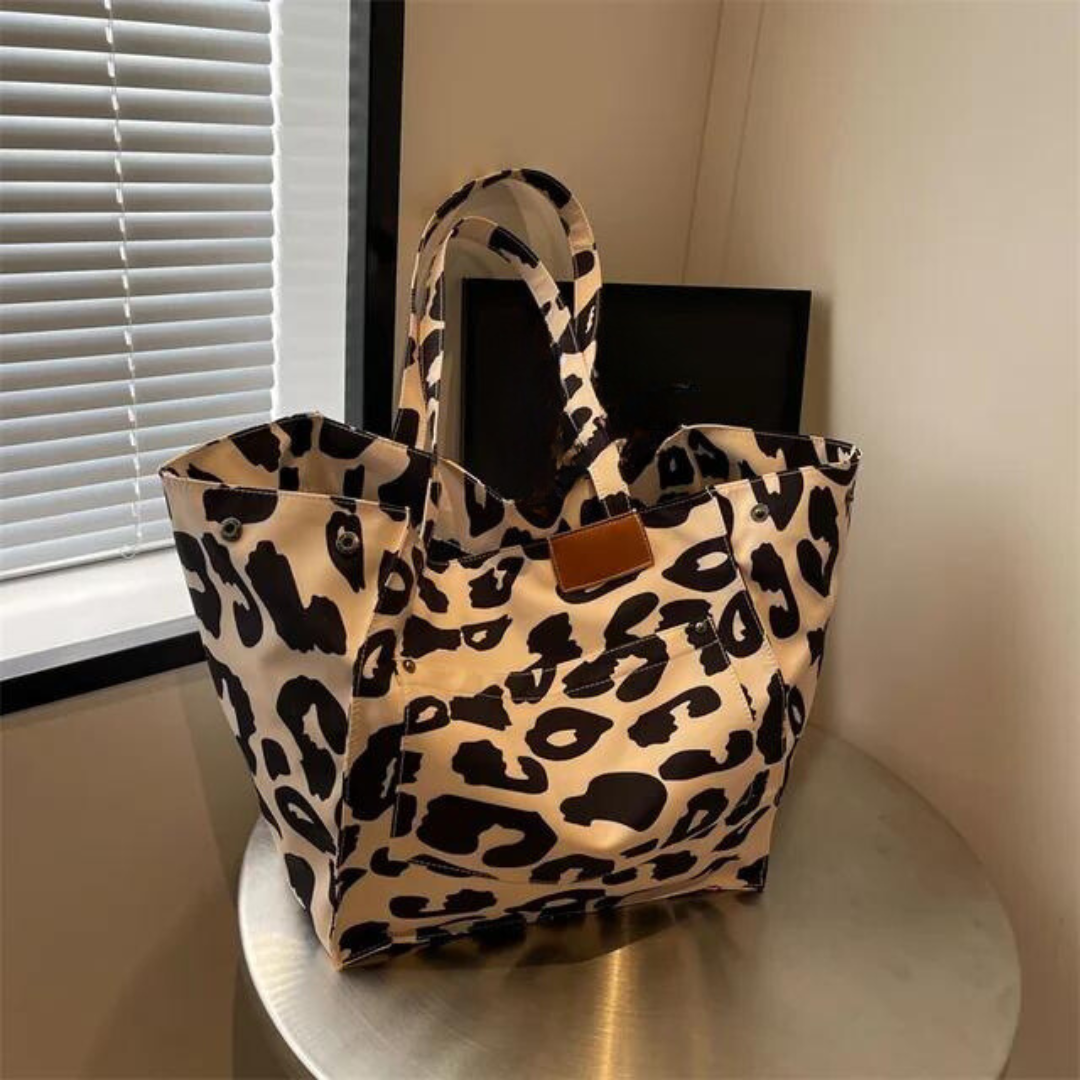 "Stilren damoversized axelväska i leopardmönstrad canvas med stora fickor, perfekt accessoar för en djärv och praktisk look."