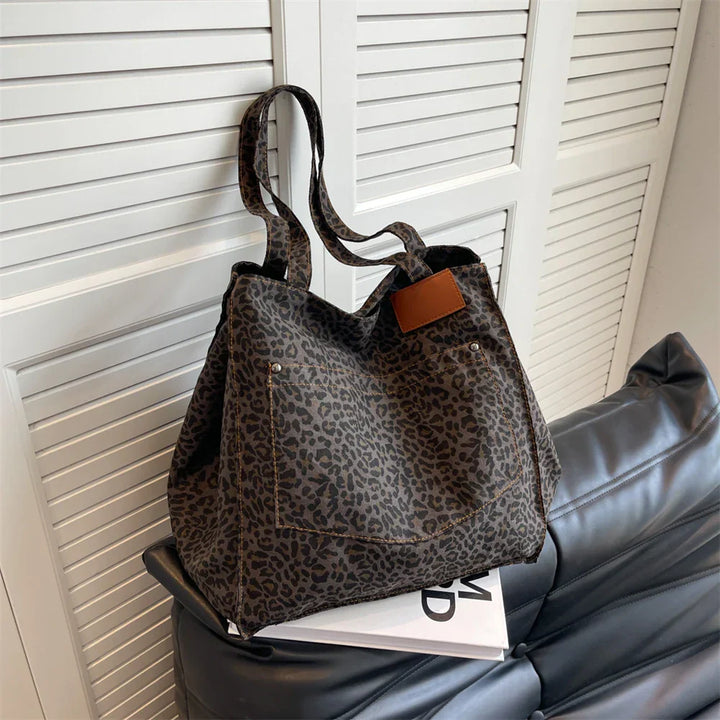 "Stilren damoversized axelväska i leopardmönstrad canvas med stora fickor, perfekt accessoar för en djärv och praktisk look."